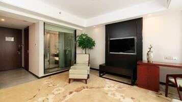 A modern living room with a large TV, a plant, and a sofa.