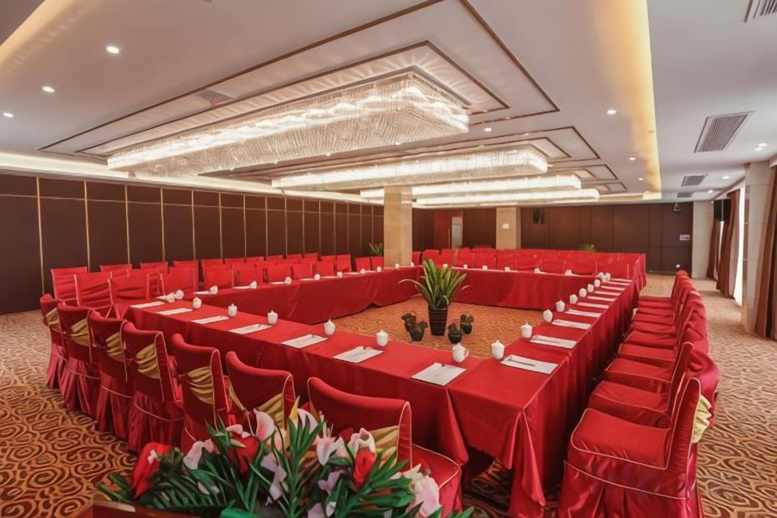 Un salón de conferencias con una larga mesa, manteles rojos y sillas.