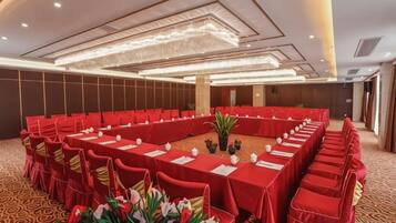 Un salón de conferencias con una larga mesa, manteles rojos y sillas.