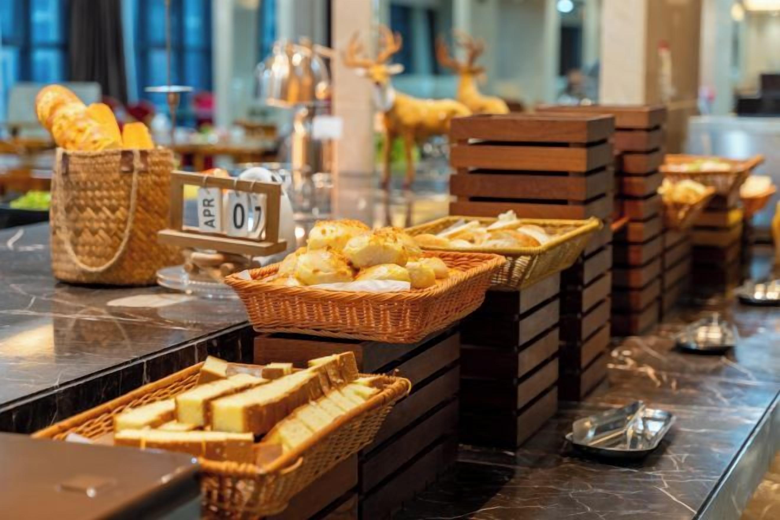Un bufé con diversas opciones de comida y cestas, incluyendo pan y productos de repostería.