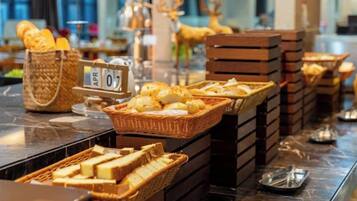 Un bufé con diversas opciones de comida y cestas, incluyendo pan y productos de repostería.