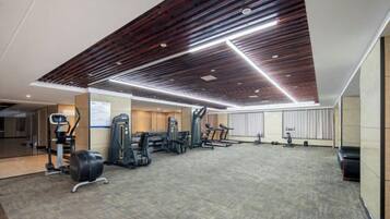 A gym with exercise equipment, a patterned carpet, and a wooden ceiling design.