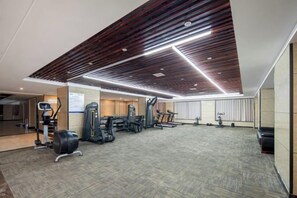 Un gimnasio con equipo de ejercicio, alfombra estampada y diseño de techo de madera.
