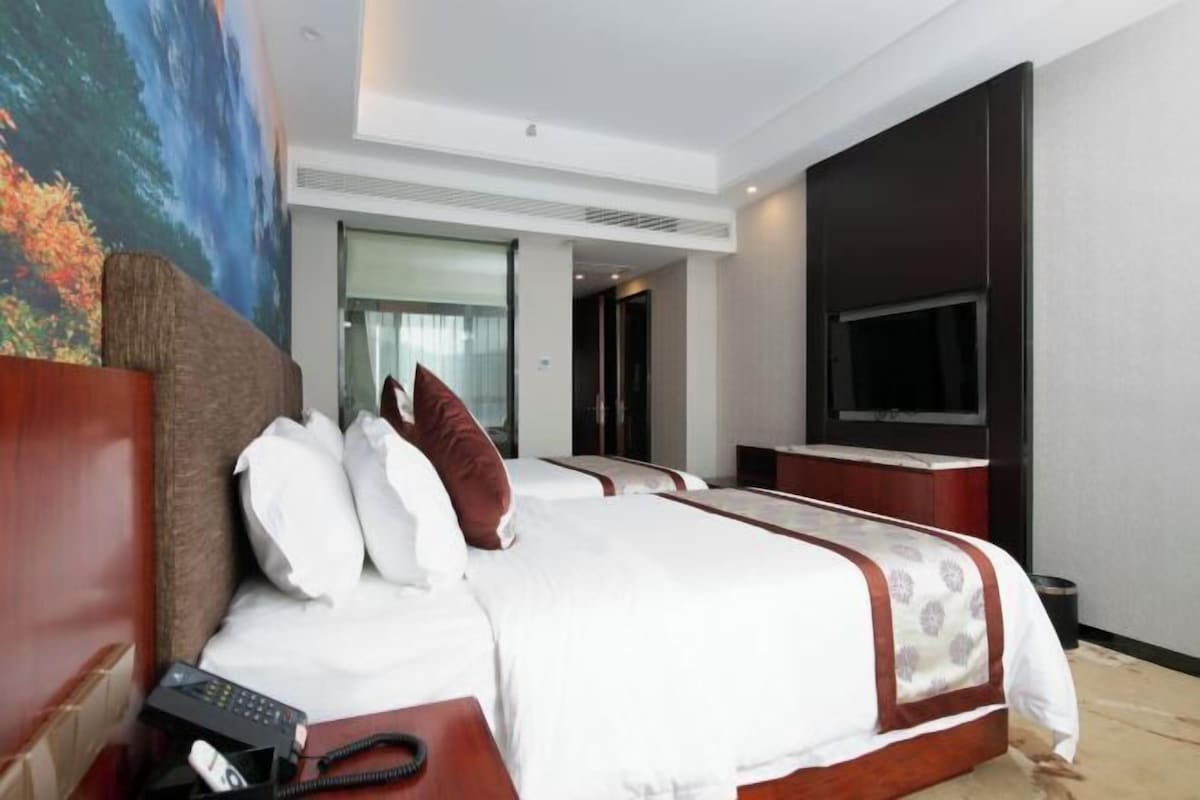 Una habitación de hotel con una cama grande, televisión y teléfono.