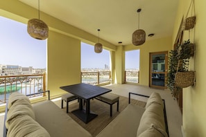A balcony with a table and chairs, a hanging plant, and a view of the city.