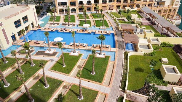 A hotel with a large central pool, multiple balconies, and well-maintained gardens. - Maison Privee - Exclusive Apt with Seafront Views over Palm Jumeirah (Dubai)