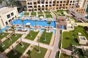 A hotel with a large central pool, multiple balconies, and well-maintained gardens.