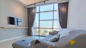 A modern bedroom with a large window, a flat-screen TV, and a sofa bed. - Executive Azure Next to New World Hotel (Petaling Jaya)
