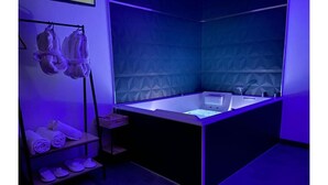 A modern bathroom with a large bathtub, a towel rack with towels, and a shelf with folded towels.