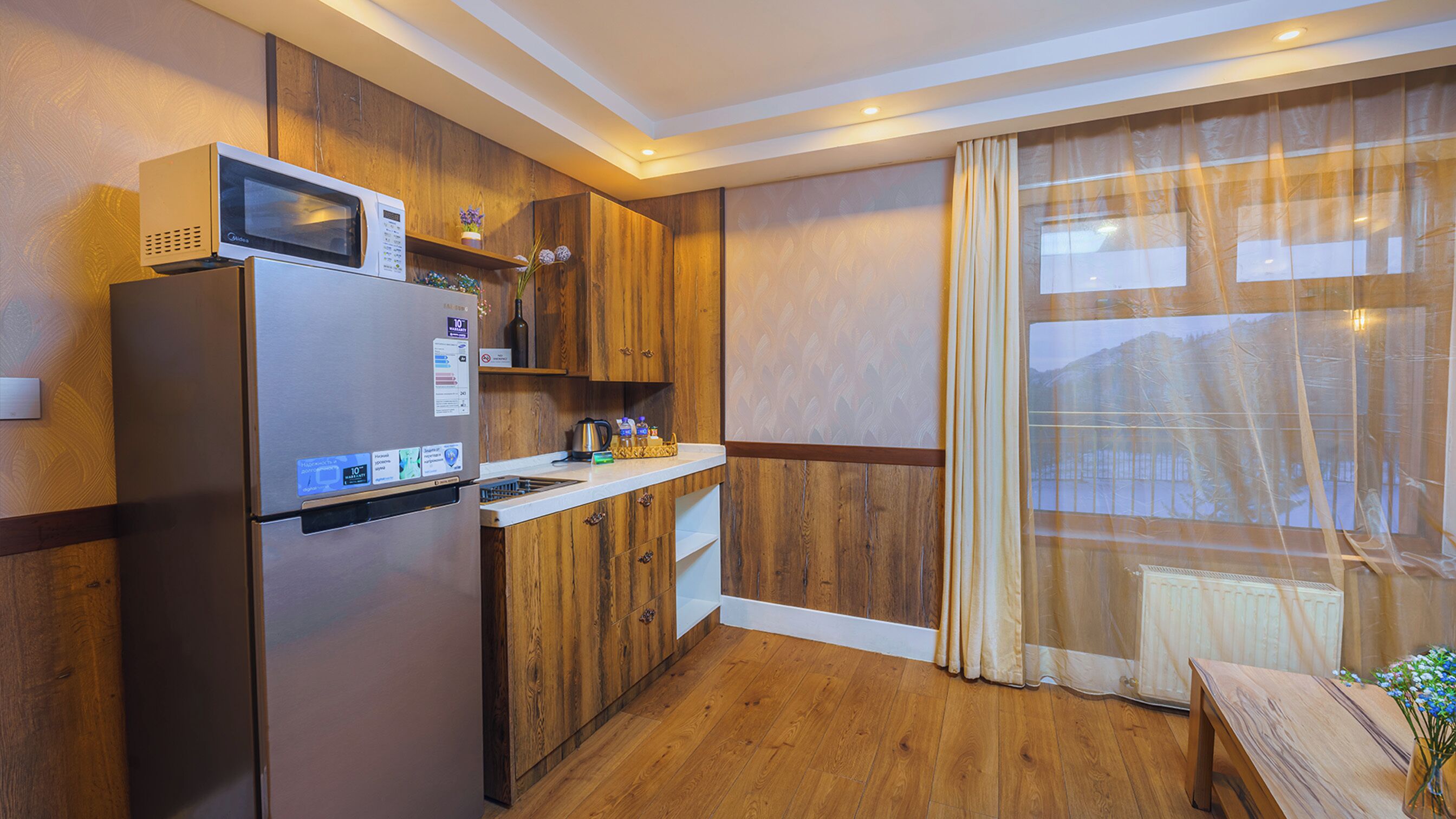 A compact kitchen with a built-in microwave, a refrigerator, and wooden cabinetry.