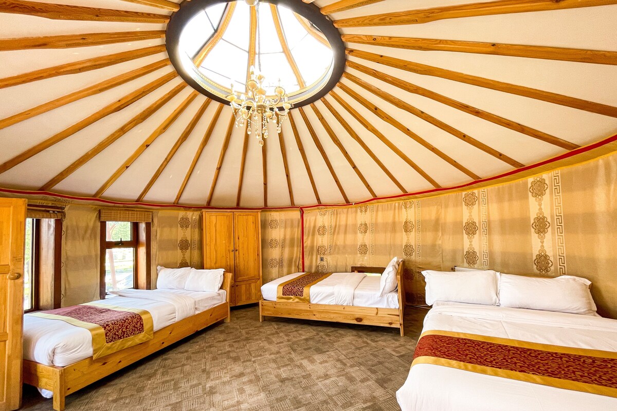 A yurt with three wooden beds, a chandelier, and a patterned wall.