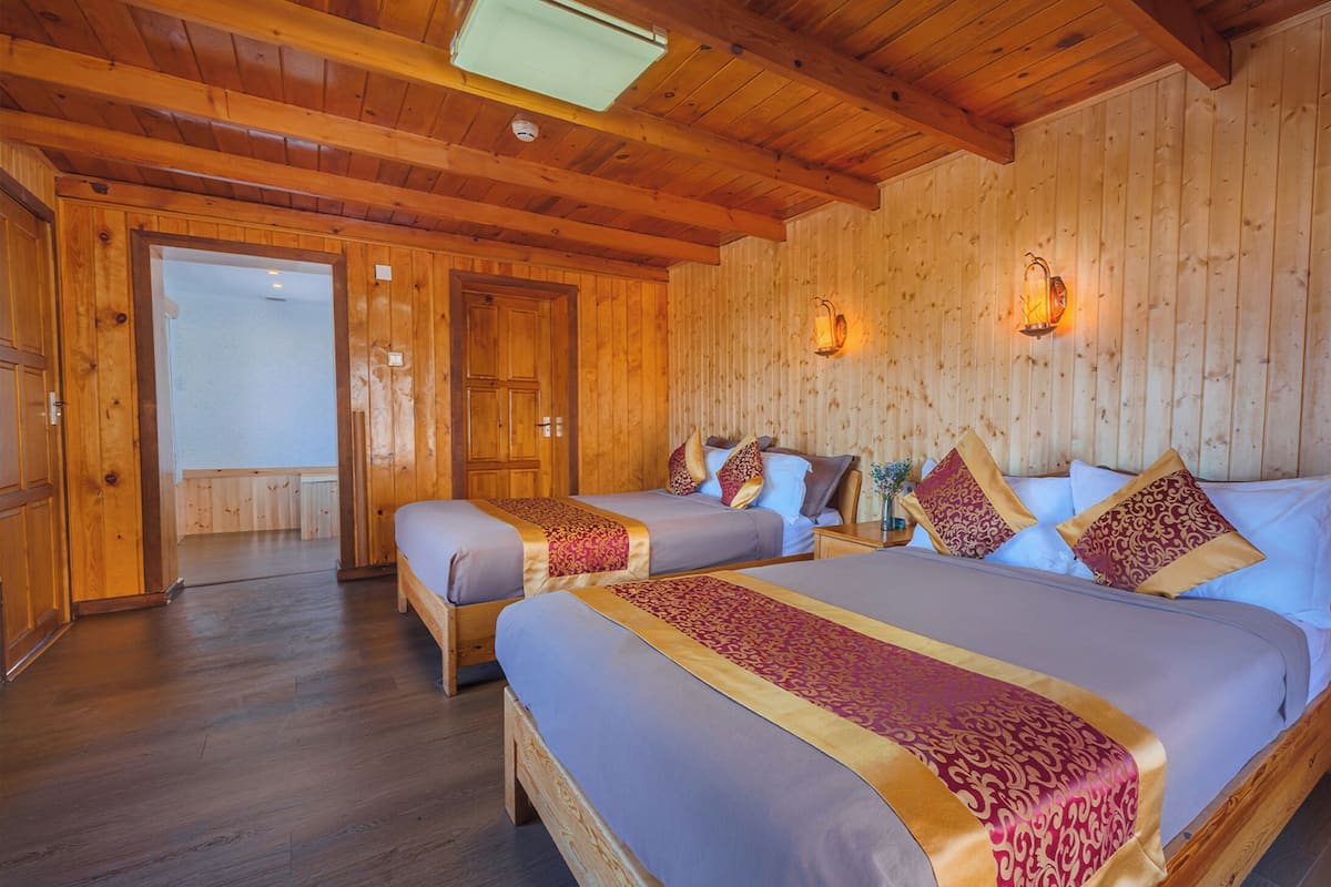 A wooden cabin room with two beds, wooden walls, and a wooden floor.