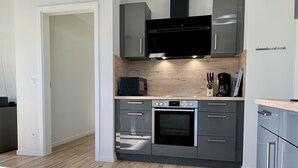 Eine moderne Küche mit grauen Schränken, einem eingebauten Backofen und einer Mikrowelle.