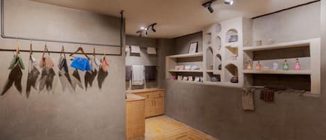 Una habitación con suelo de ladrillo, armarios de madera y estantes con artículos de tocador.