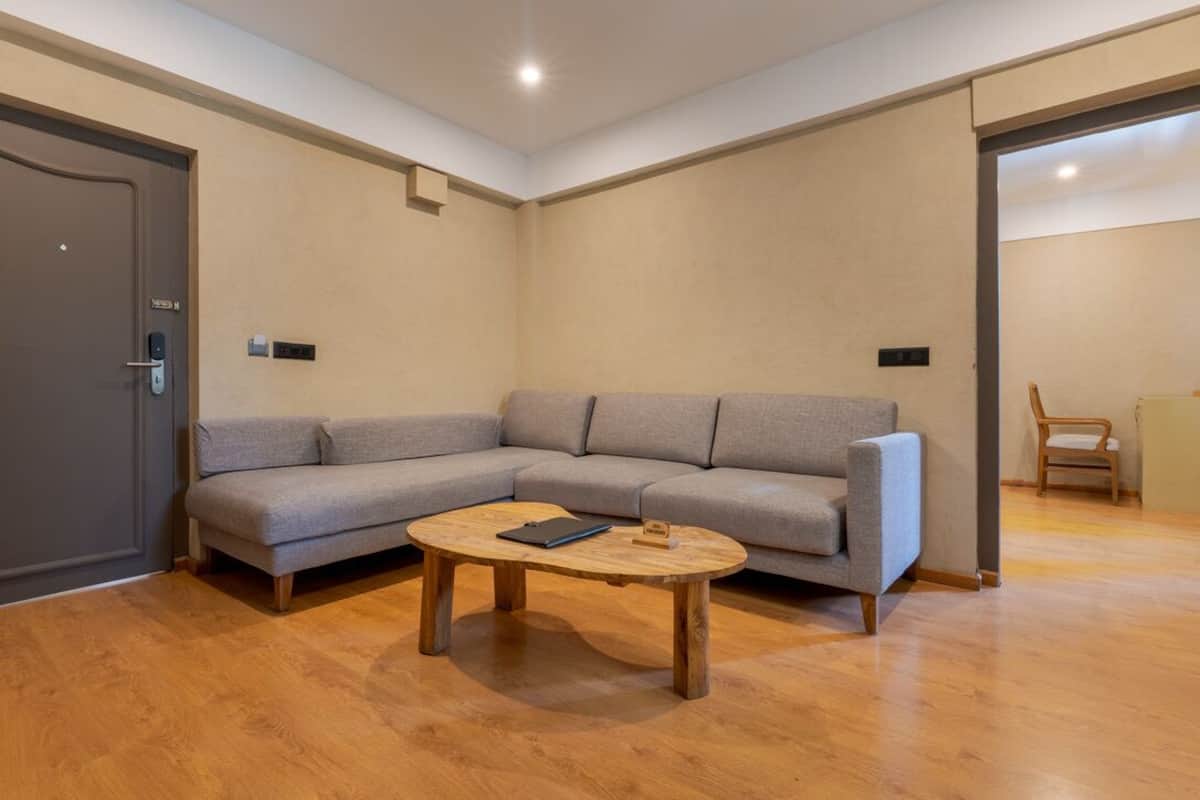 Ein modernes Wohnzimmer mit einem grauen Ecksofa, einem Holztisch und einer Tür mit Kartenleseöffnung.
