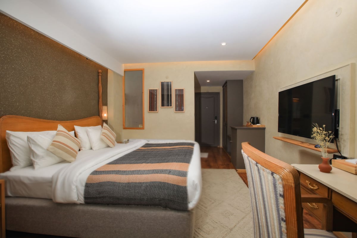 Ein Hotelzimmer mit Bett, Schreibtisch, Fernseher und Spiegel.
