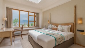 A bedroom with a large bed, a desk, and a window with a view of mountains. - The Pal (Leh)