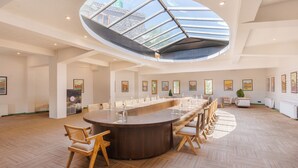 A spacious conference room with a high ceiling, a central round table, and a skylight. - The Pal (Leh)