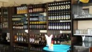Una zona de bar con estantes llenos de diferentes botellas y copas.