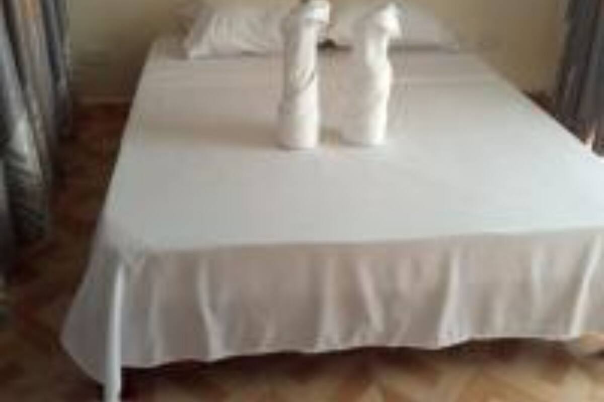 A bed with white linens and two white towels placed on it.