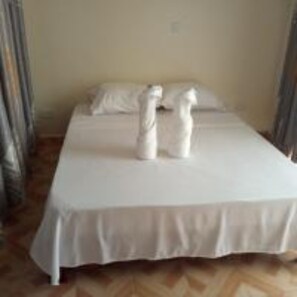 Una cama con sábanas y toallas blancas.