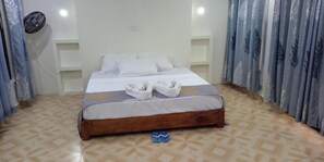Una cama bien hecha con sábanas y toallas blancas, un cabecero de madera y un suelo con diseño.