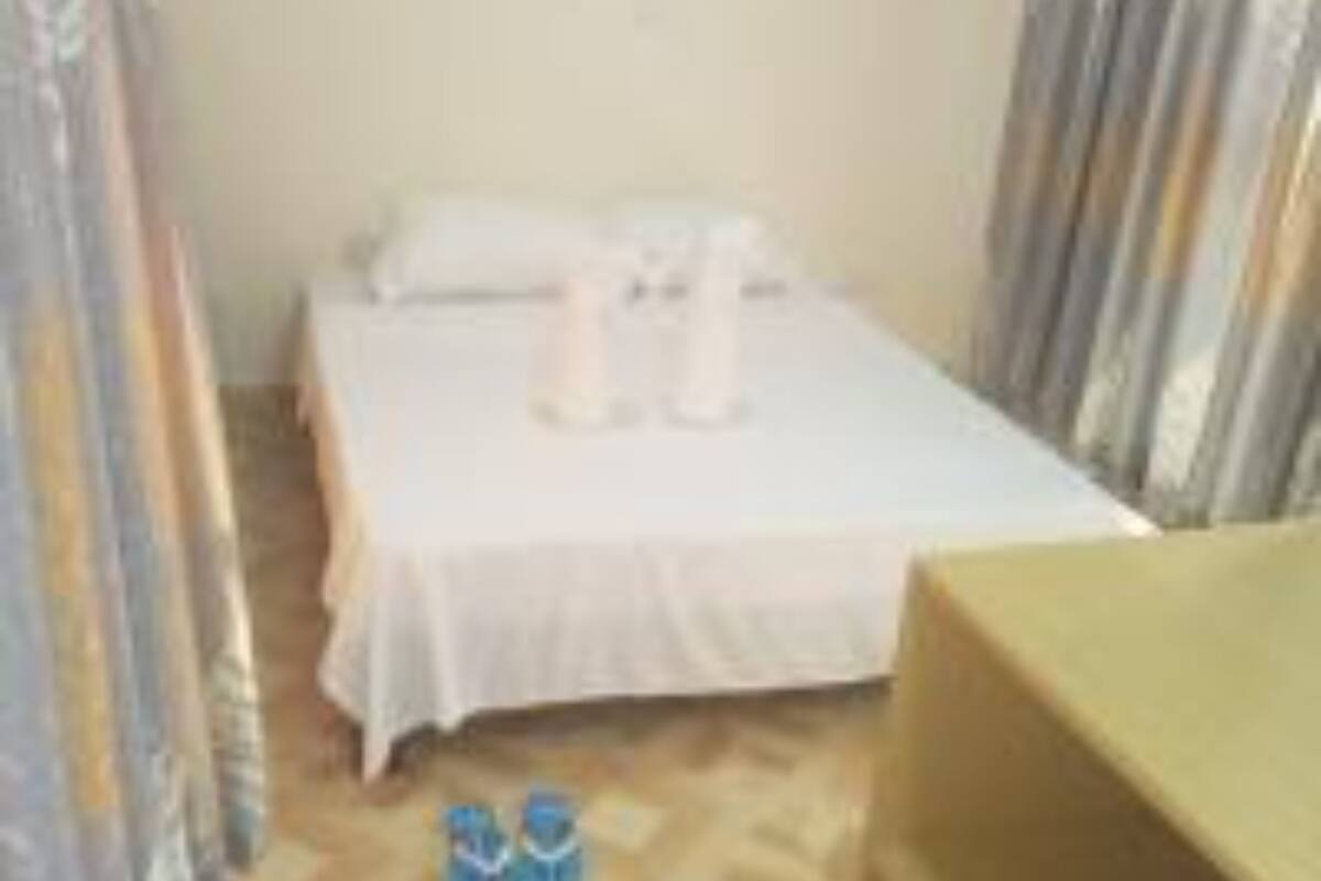 A small, simple room with a bed, a nightstand, and a pair of shoes on the floor.