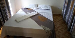 Una habitación de hotel con una cama, una mesa y cortinas.