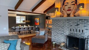 A modern living room with a fireplace, a dining area with a table set for four, and a bookshelf filled with books. - Luxurious Getaway on the Lake with hot tub, pool table, boat dock, covered porch (Langlois)