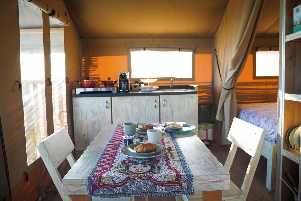 Una cocina acogedora con una mesa de comedor preparada para dos personas, con mantel que presenta un diseño bordado en el centro.