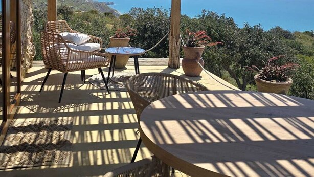 A wooden pergola with outdoor seating, overlooking a coastal landscape.