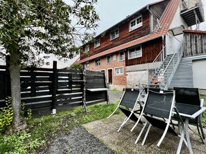 A courtyard with a wooden fence, a staircase, and outdoor seating.