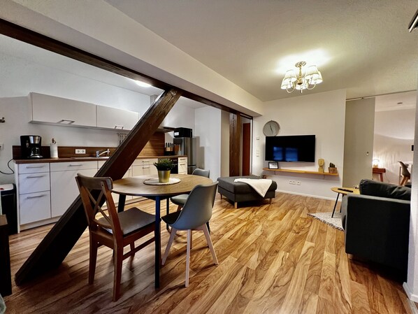 A modern living space with a dining area, kitchen, and a TV mounted on the wall.