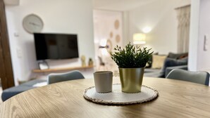 A round wooden table with a woven placemat, a grey mug, and a green plant in a gold pot. - Modern apartment with charm (Kehl)