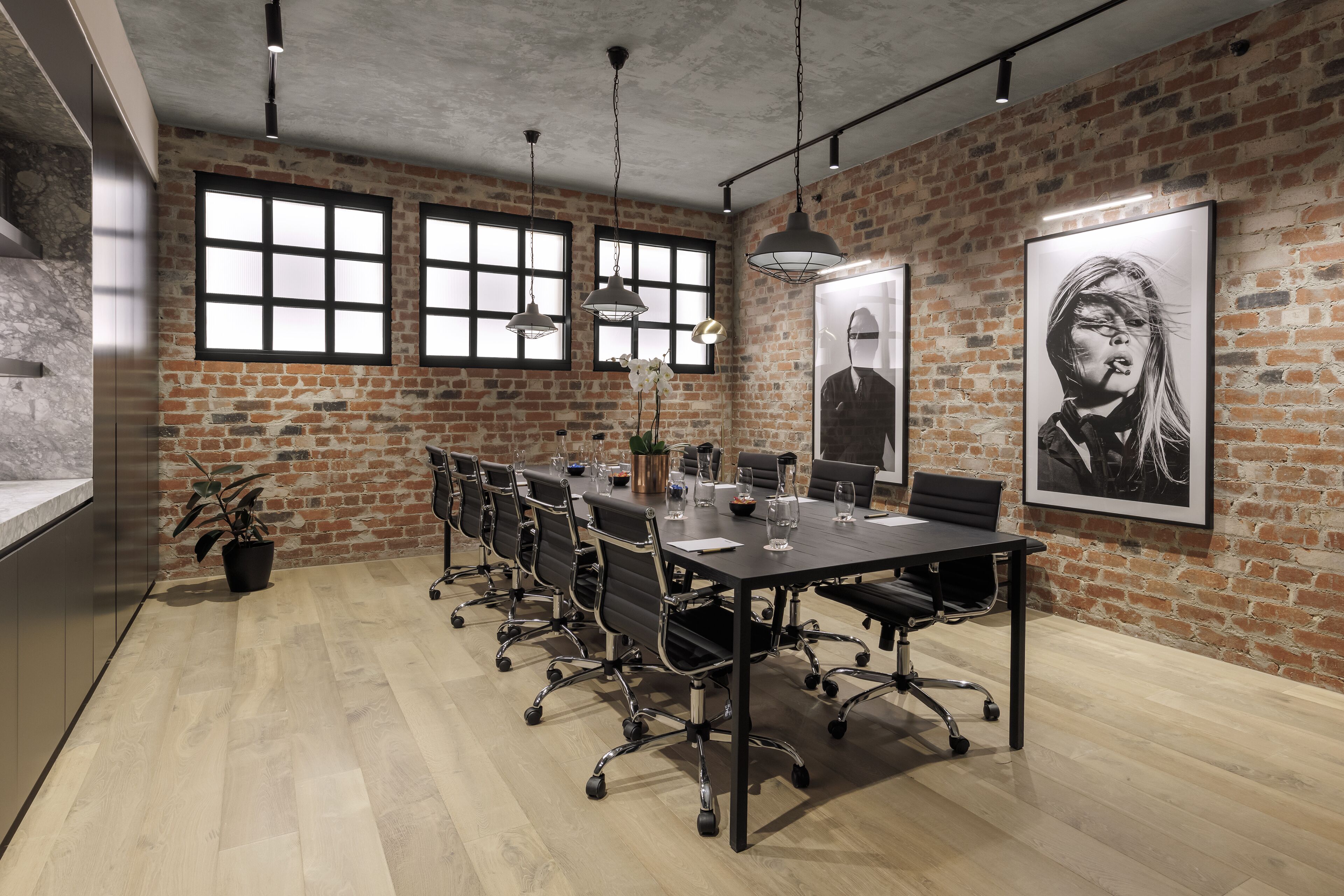 A conference room with a long table, black chairs, and a brick wall.