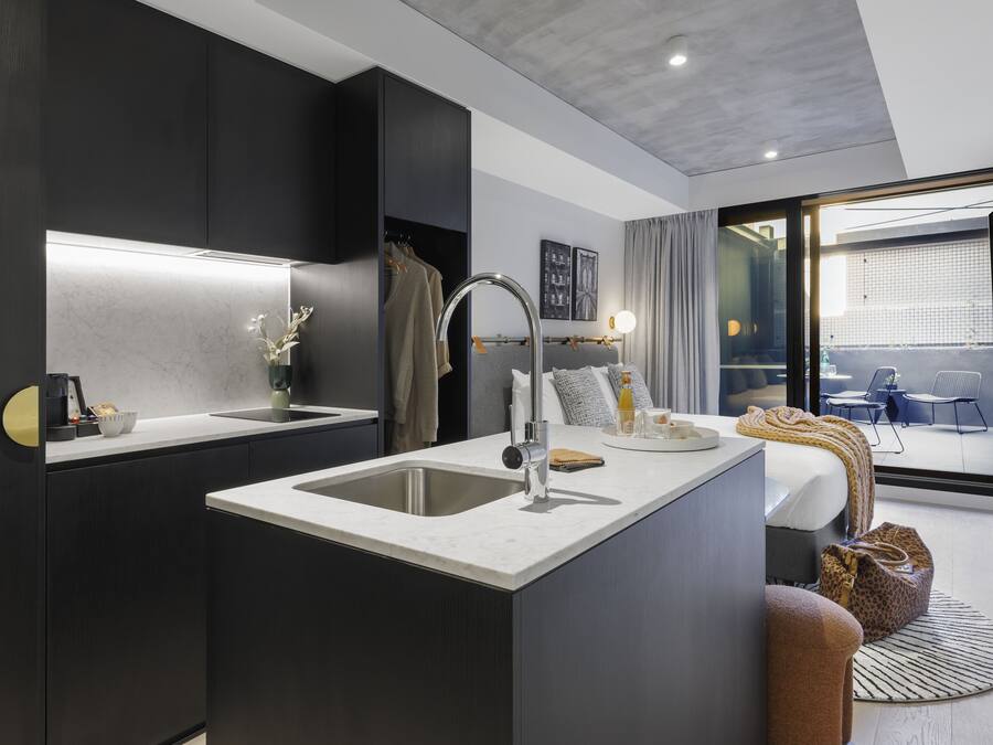 Habitación de hotel moderna con zona de cocina, un ventanal grande y un área de descanso con vistas.
