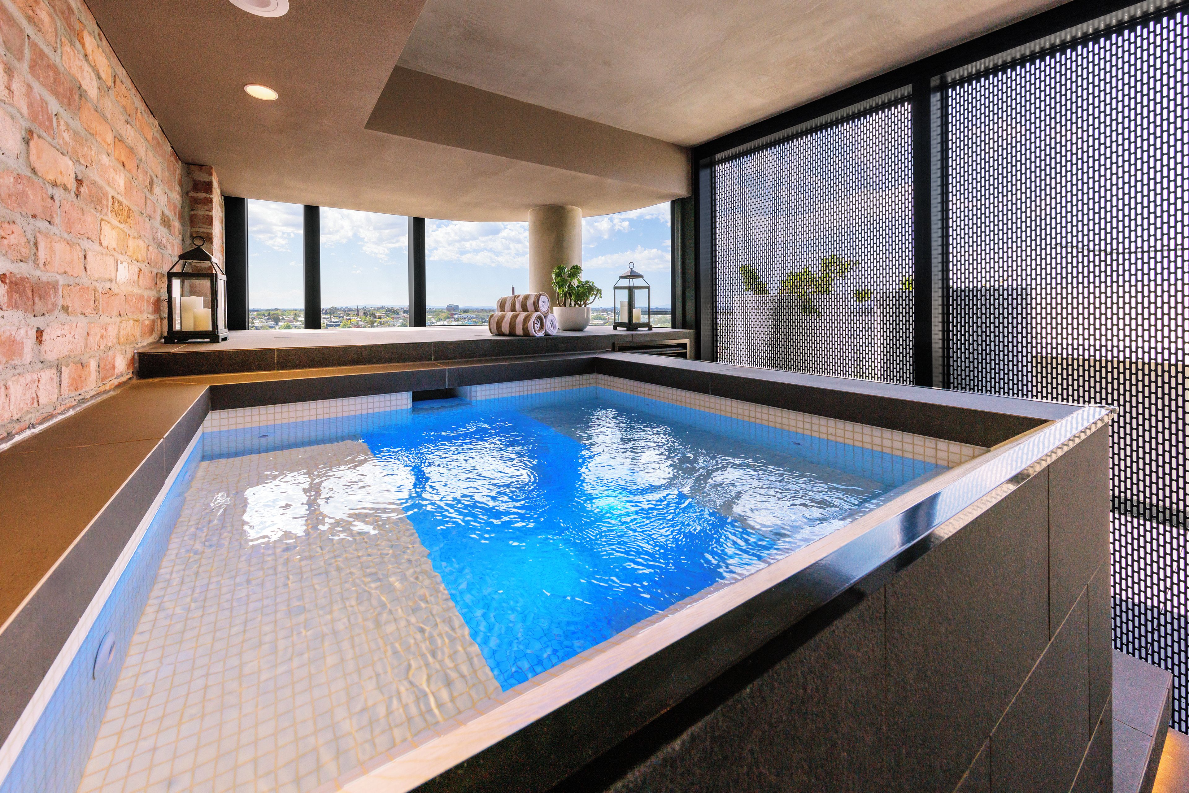 Piscina com vista para o horizonte urbano, uma parede de tijolos e design de interiores moderno.