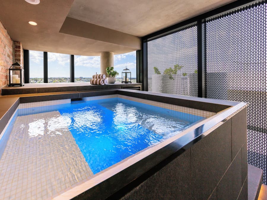 Piscina com vista para o horizonte urbano, uma parede de tijolos e design de interiores moderno.