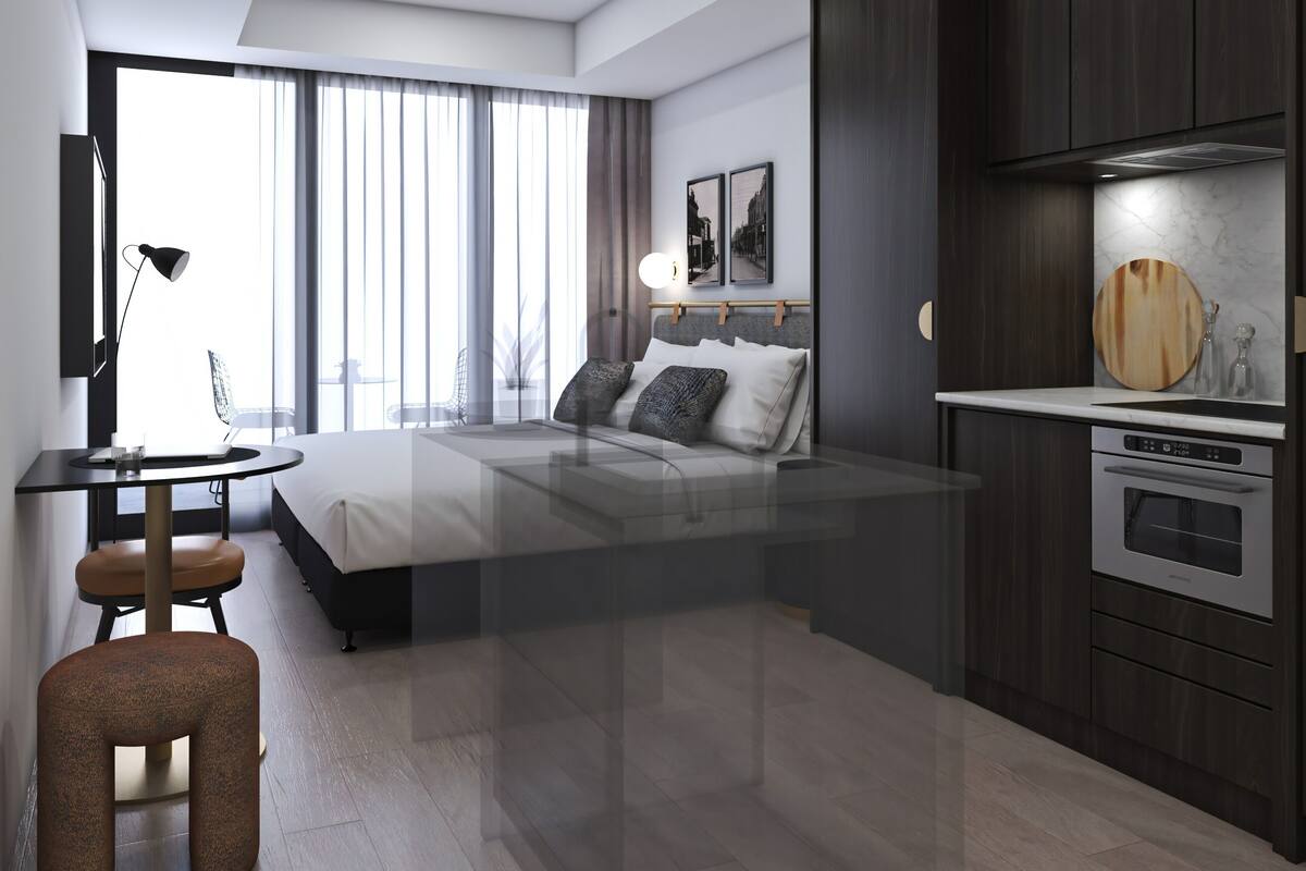 Una habitación de hotel moderna con cama, escritorio, silla y kitchenette.