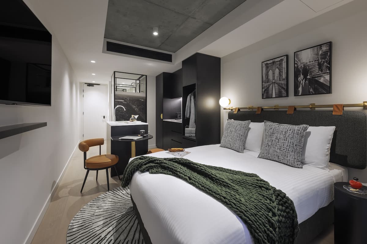 Un dormitorio moderno con una cama grande, un escritorio, una silla y un espejo.