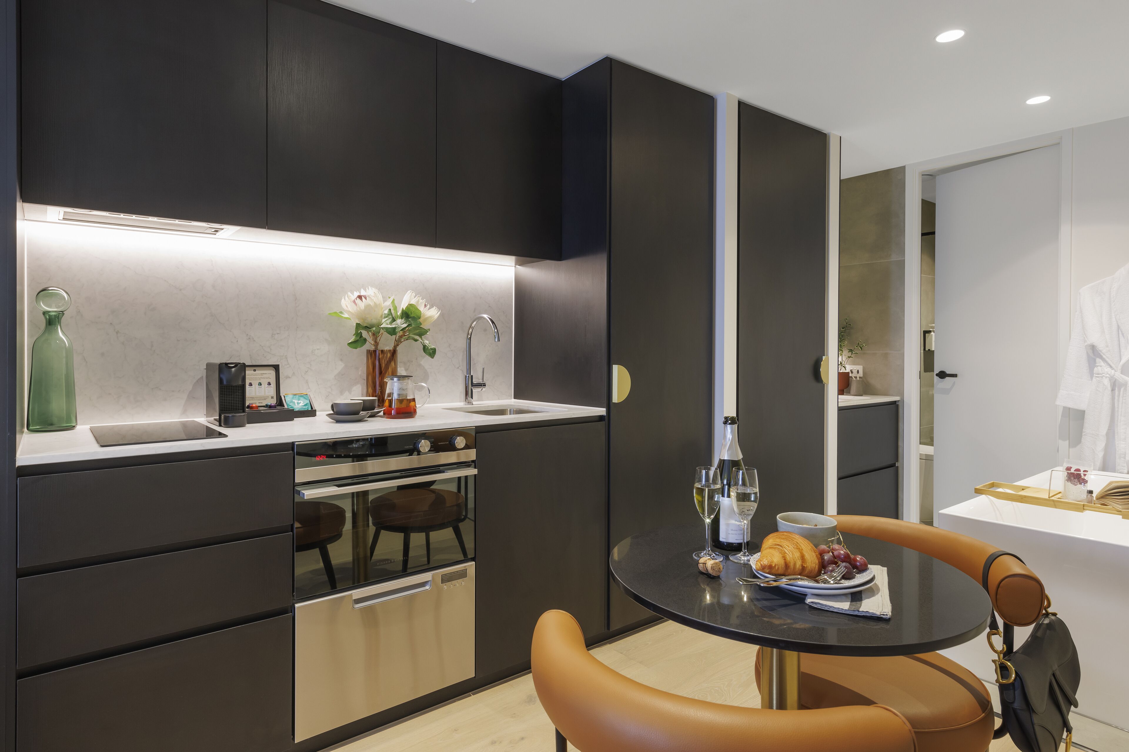 Eine moderne Küche mit Essbereich, ausgestattet mit einem Backofen, einer Kaffeemaschine und einer Vase mit Blumen auf der Arbeitsfläche.