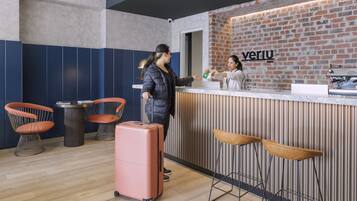 A reception area with a brick wall, a reception desk, and two bar stools.