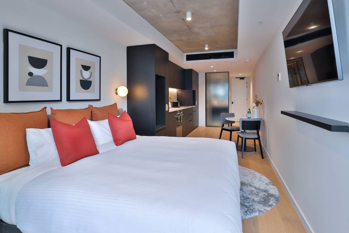 Una habitación de hotel moderna con una cama grande, un escritorio y un televisor.