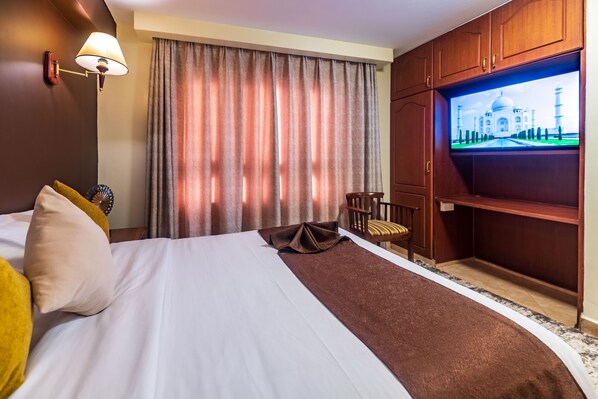 A hotel room with a bed, a television, a desk, and a chair. - Samra Hotel (Nairobi)
