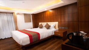 A hotel room with a wooden bed, a nightstand, and a coffee maker. - MeroStay 001 Hotel Kailash Kutee (Kathmandu)