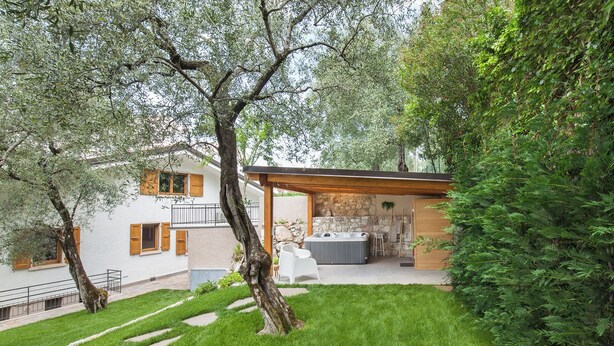 Ein modernes Haus mit einer Steinwand, einem Whirlpool und einer überdachten Terrasse.