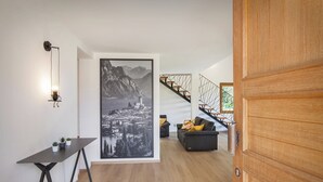 Ein modernes Interieur mit einer Holztreppe, einem Schwarz-Weiß-Stadtbild, einem kleinen Tisch mit Pflanzen und einer Couch mit Kissen.