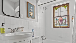 A bathroom with a white vanity, a toilet, a bathtub, and a shower. - One-bedroom-City Livin' (Saint Louis)