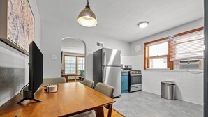A modern kitchen with a stainless steel refrigerator, a stove, and a trash bin. - One-bedroom-City Livin' (Saint Louis)