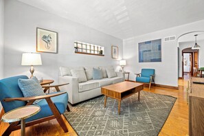 Un salon moderne avec un canapé, des fauteuils, une table basse et un tapis à motifs.
